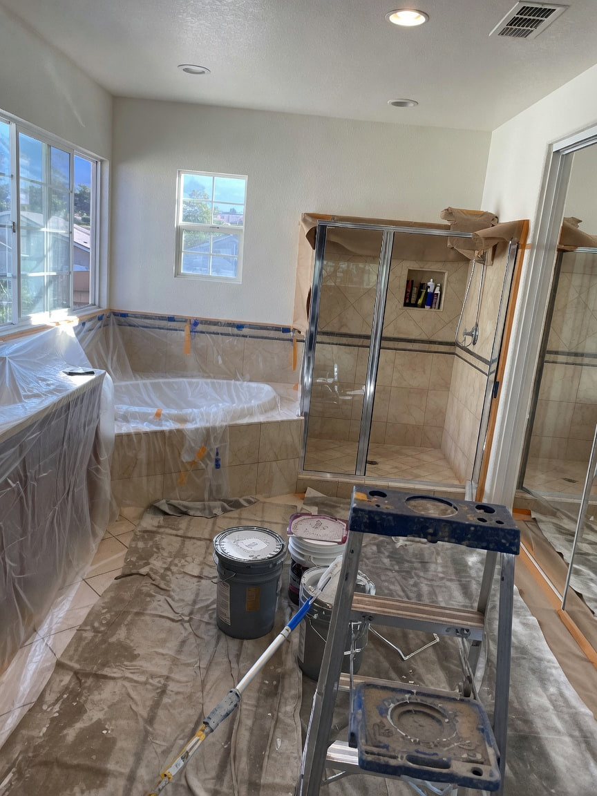 Bathroom remodel in progress with paint supplies and protection