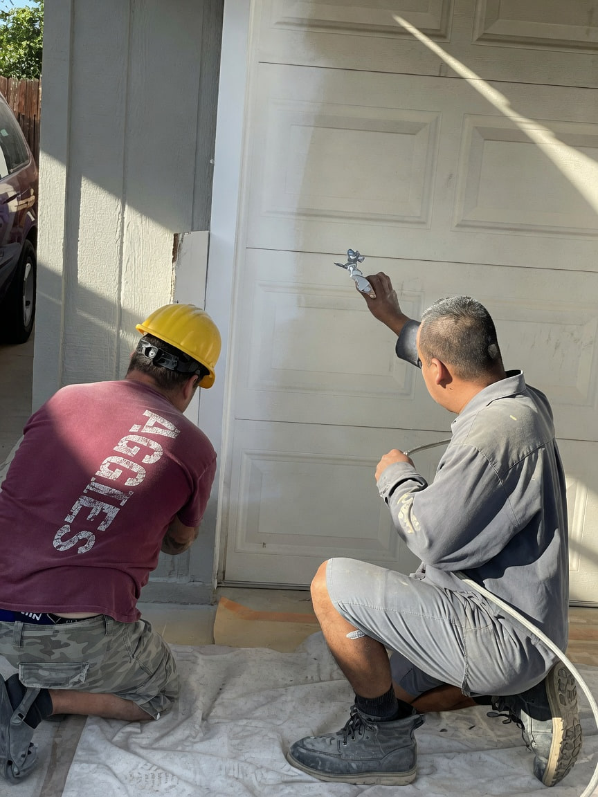 Crew members carefully painting a garage door